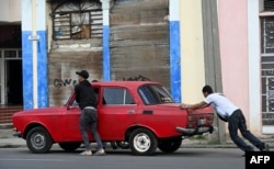 Cubanos empujan un automóvil cerca de una gasolinera en La Habana el 11 de diciembre de 2024. YAMIL LAGE / AFP