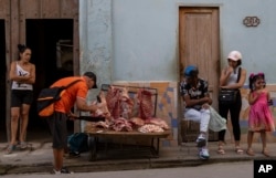 Un vendedor de carne de cerdo corta trozos para los compradores que esperan su turno en la acera de La Habana, Cuba, el 14 de febrero de 2025. (Foto AP/Ramon Espinosa)